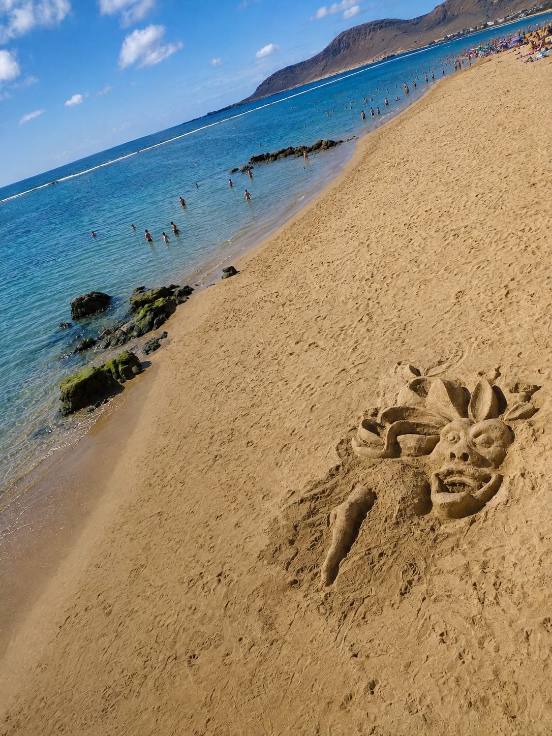 Las Canteras-stranden i Las Palmas med sandskulptur og utsikt mot fjellene