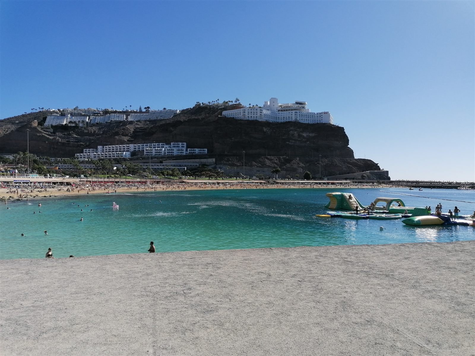 Playa de Amadores med badegjester og hotellet på klippen